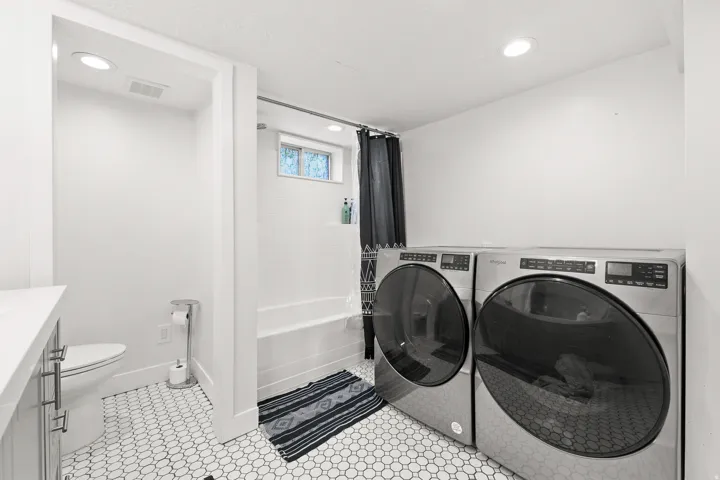 White tiled flooring, recessed ceiling lighting, a built-in bathtub with subway tile surround, and a vanity with a white countertop