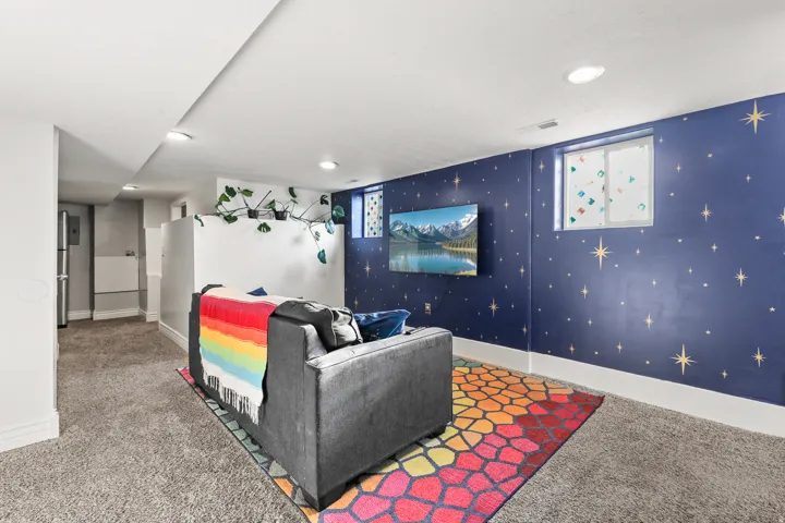 Recessed lighting illuminating a carpeted living space with a distinct accent wall and a built-in shelf