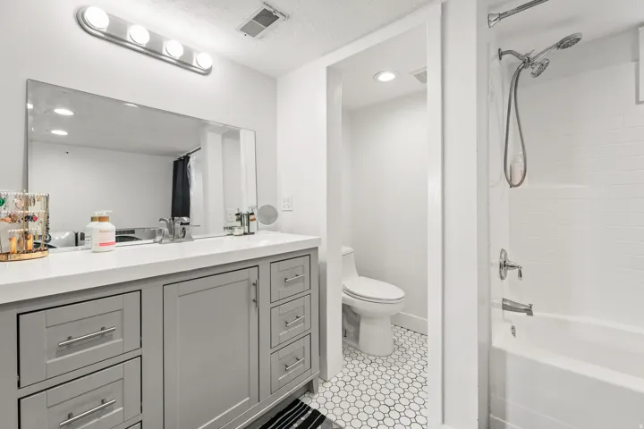Gray vanity with multiple drawers, white countertop, and large rectangular mirror