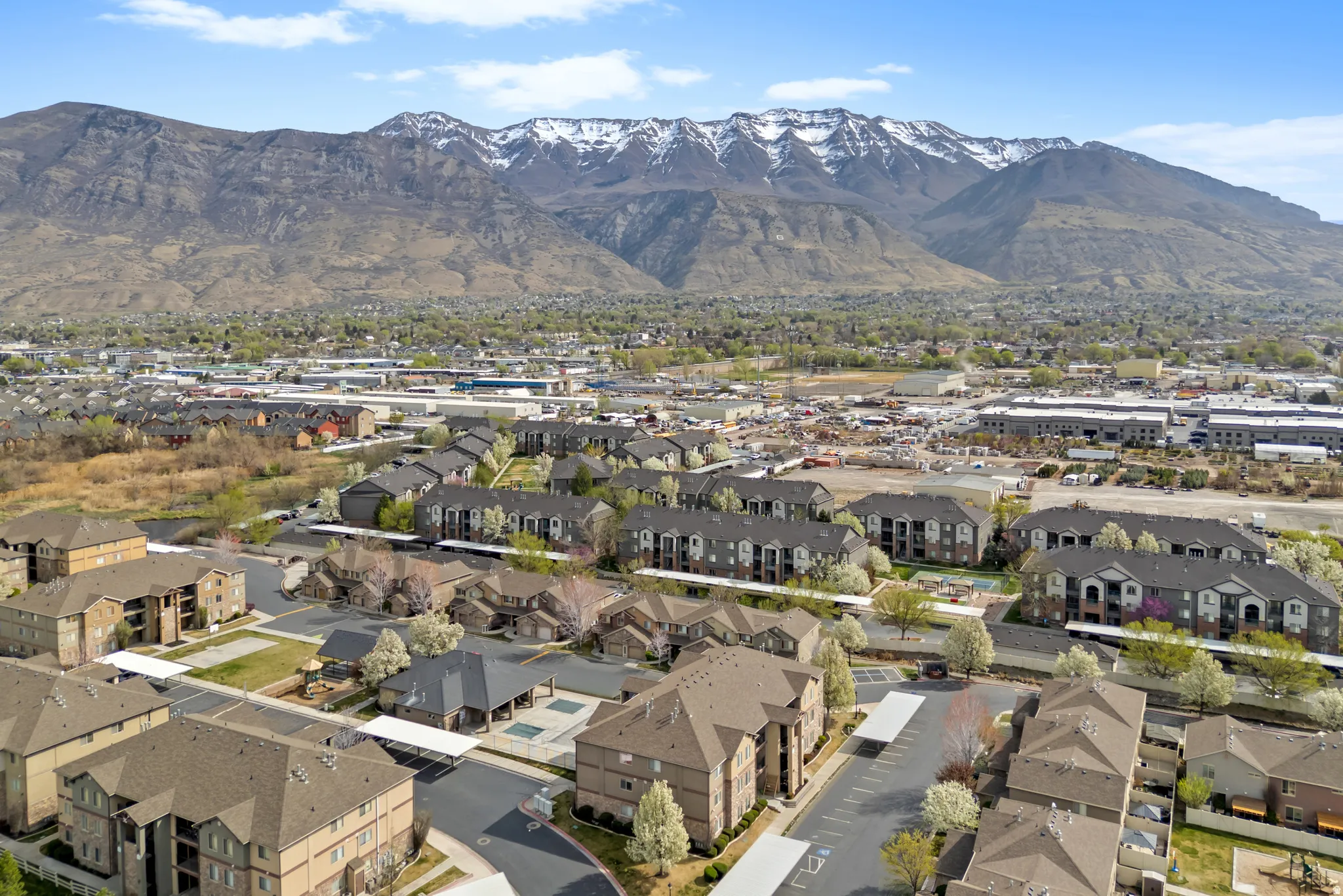 Aerial perspective showcasing a residential community with multi-story buildings, covered parking areas, and mature trees