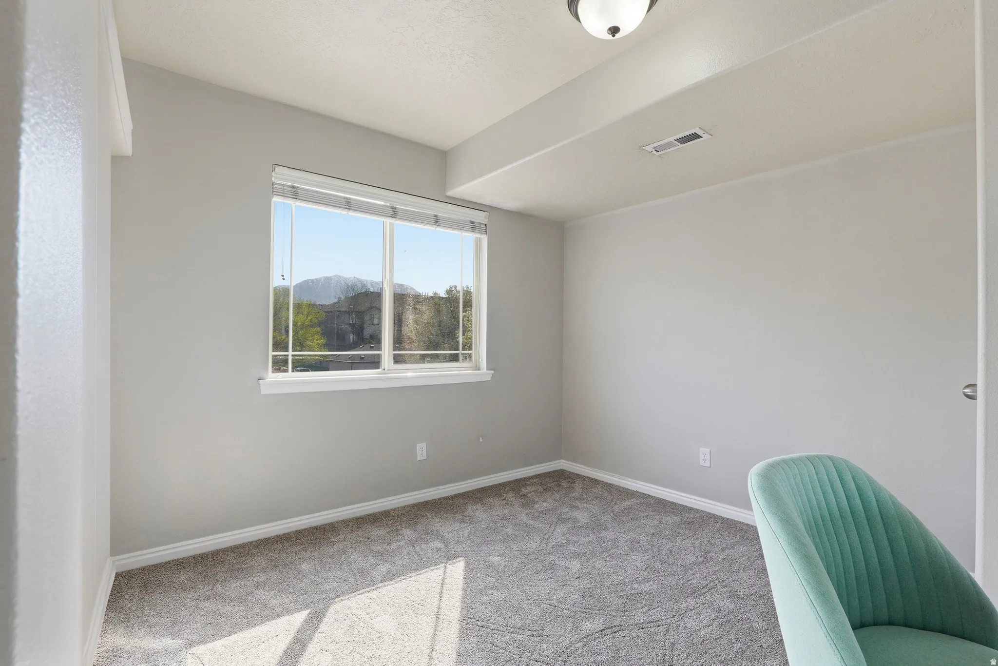 Expansive window framing a mountain backdrop, complemented by soft gray carpeting and white trim