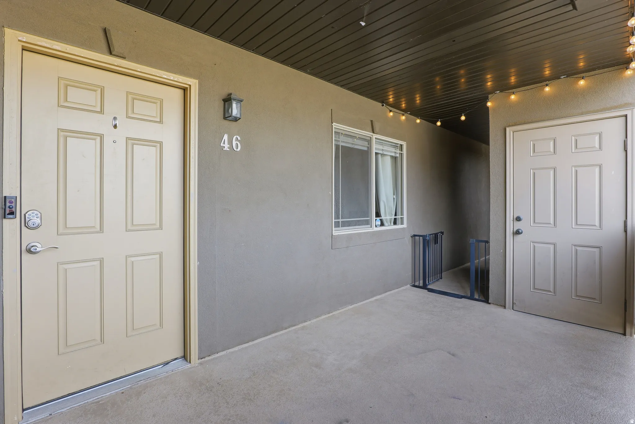 Entryway featuring a panel door with smart lock access, exterior wall sconce, and an adjacent window with horizontal blinds