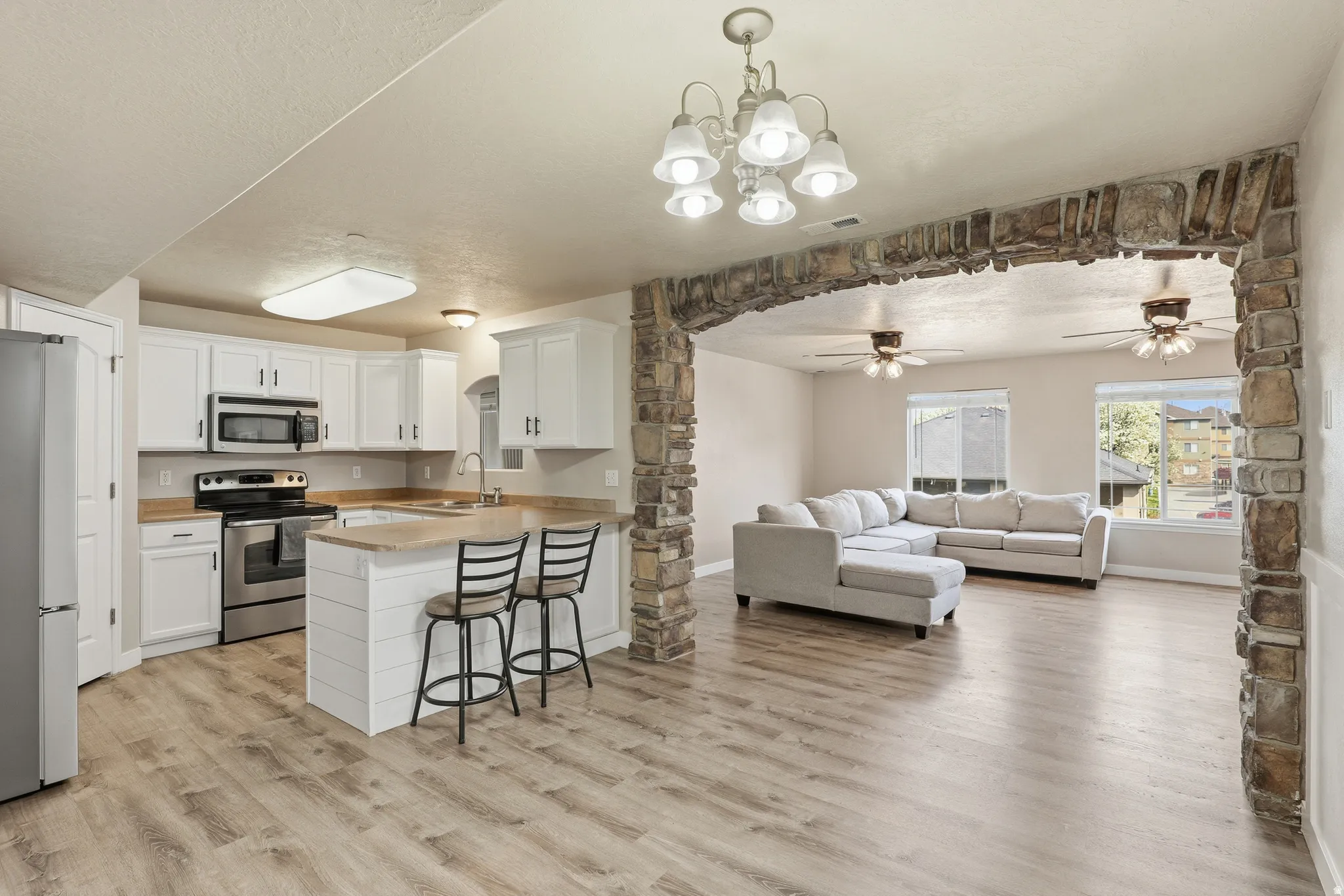 Kitchen featuring white cabinetry, stainless steel appliances, and wood-finish flooring