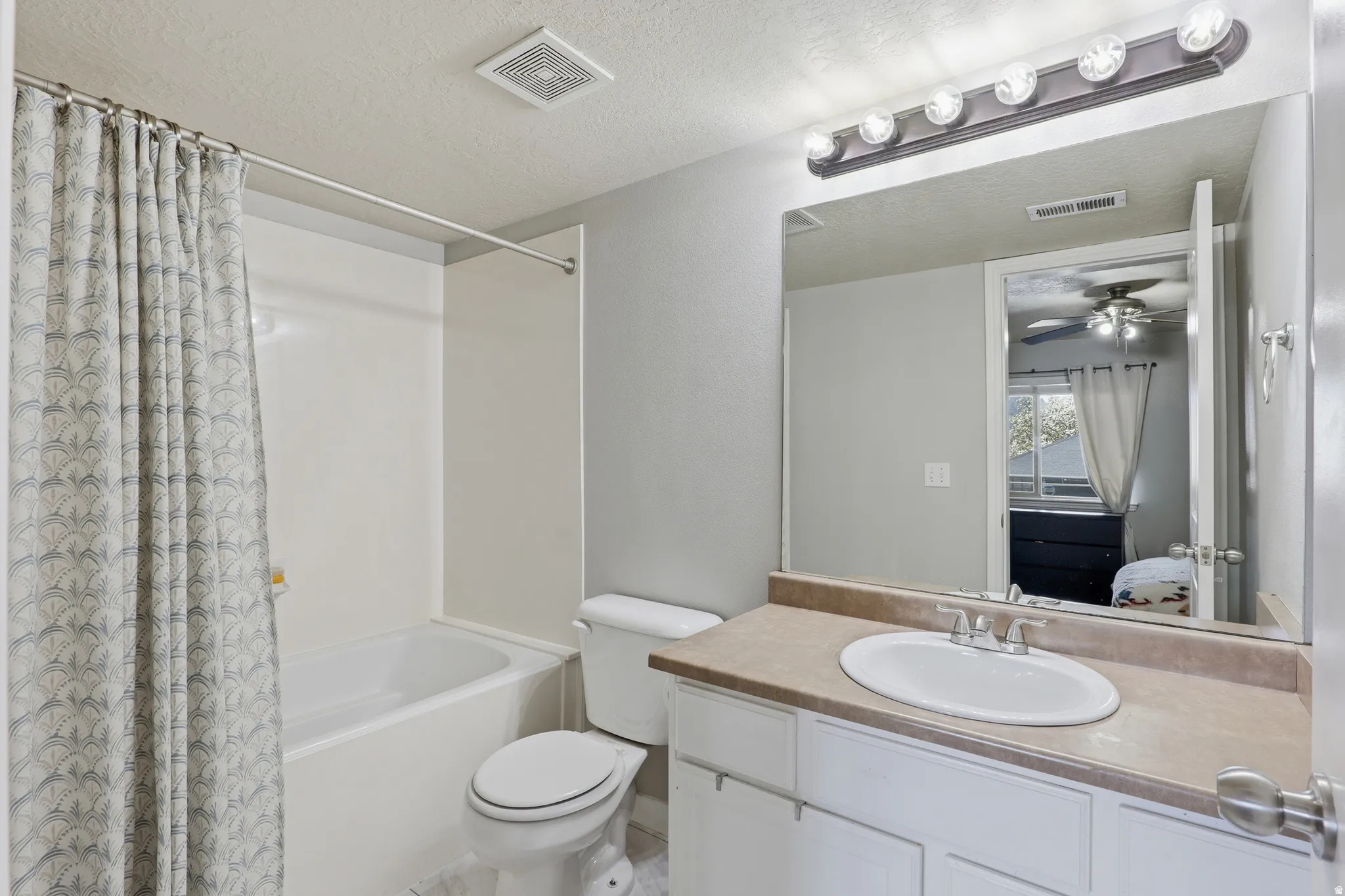 White vanity with integrated sink, rectangular mirror, and bar lighting