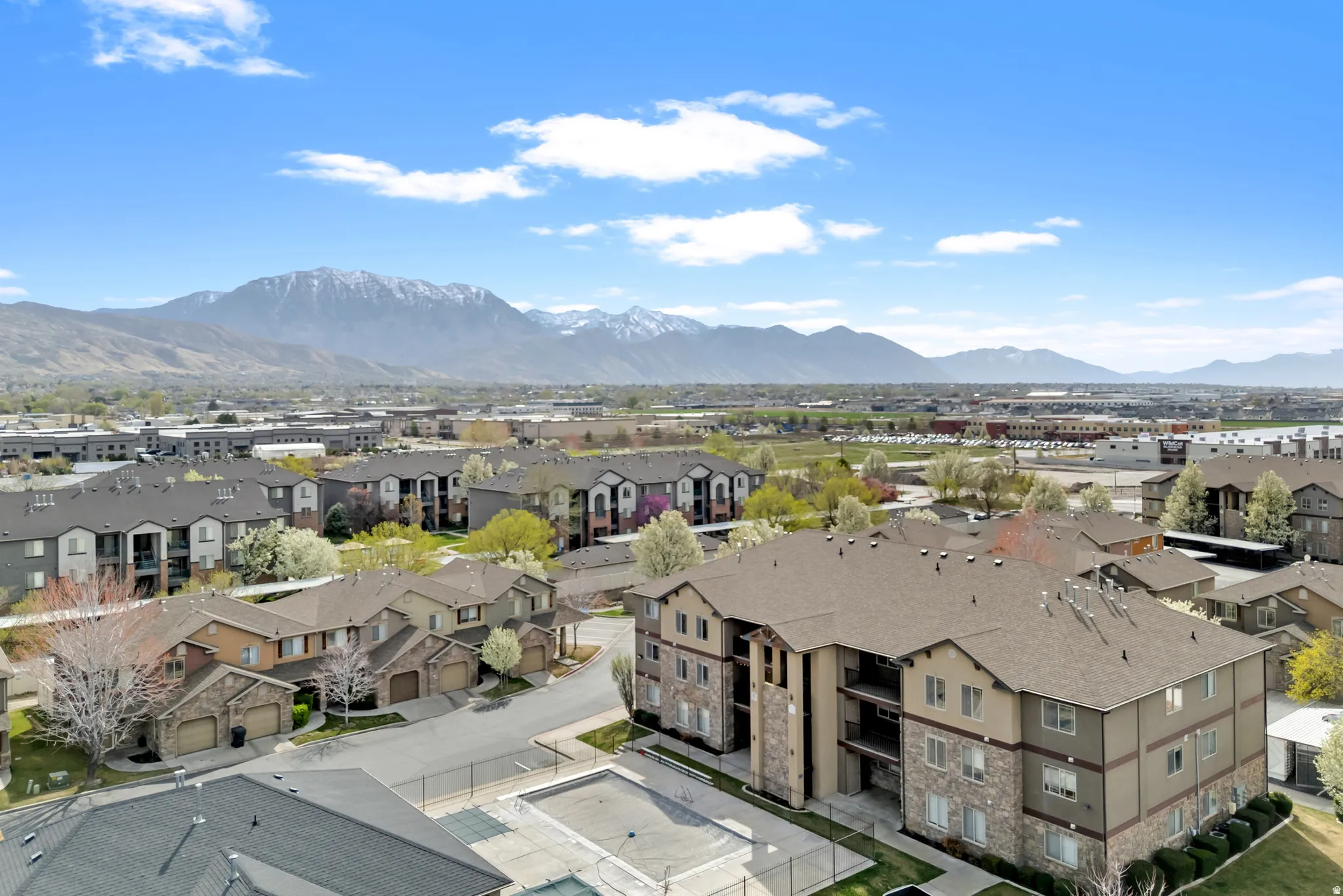 Community featuring multi-story residential buildings, townhomes, and a central swimming pool