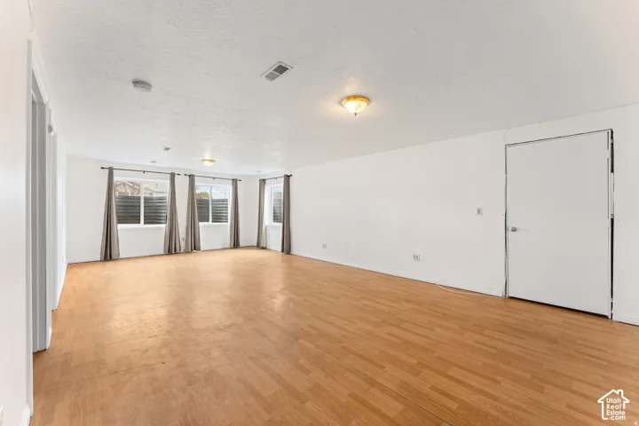 Spacious room featuring light wood-finish flooring and multiple windows