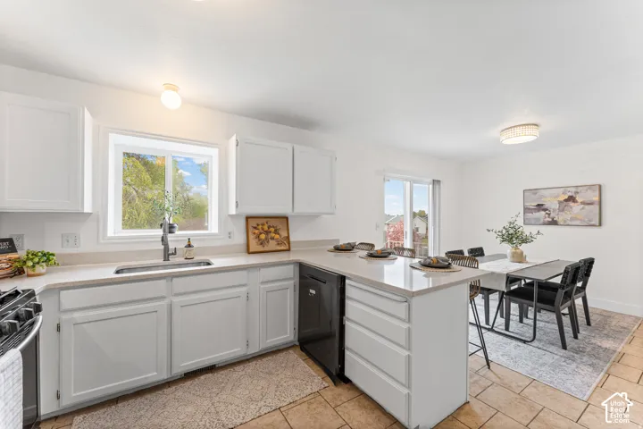 White shaker cabinetry, light-toned countertops, tile flooring, window over sink, and a sliding glass door