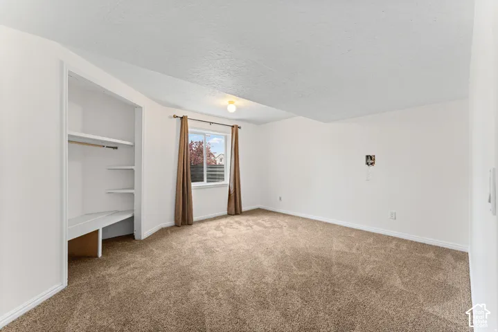 Built-in shelving and hanging rod, neutral-toned carpeting, and a window with natural light