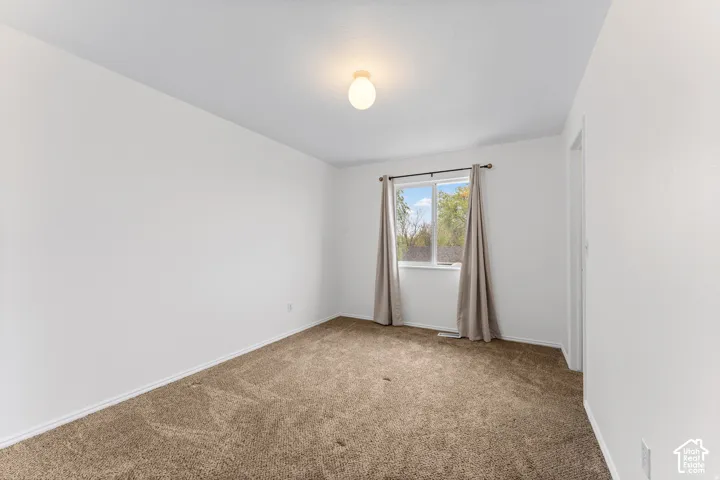 Neutral wall color, carpet flooring, flush mount lighting, single window, and a door frame