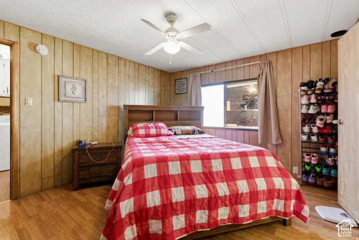 Wood-finish flooring, paneled wall finishes, and a ceiling fan with integrated lighting