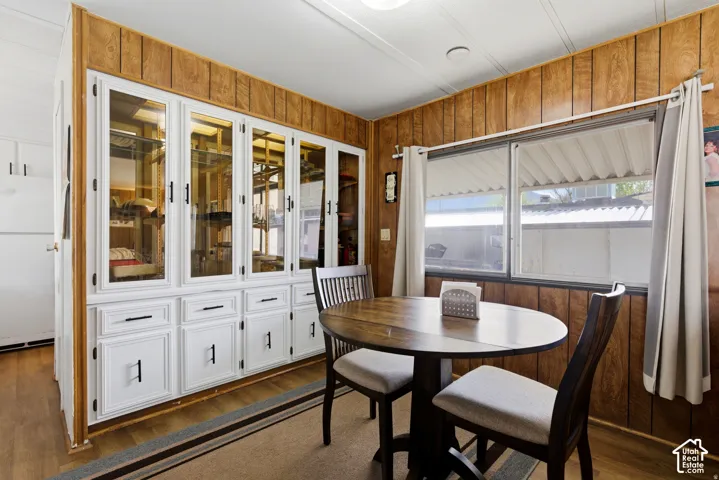 Built-in cabinetry with glass-front uppers, wood-finish wall paneling, and wood-finish flooring