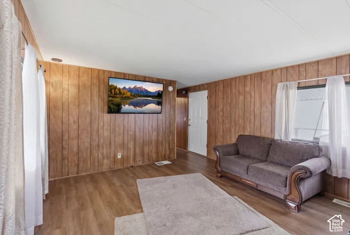 Wood-finish flooring throughout, light-colored walls, and windows with sheer white curtains