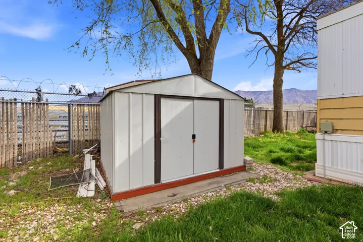 Metal storage shed on a concrete pad, surrounded by a natural grass and gravel ground cover