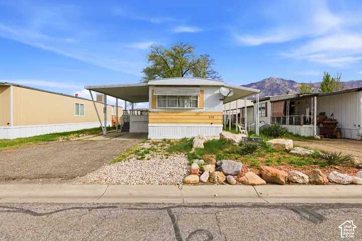 Exterior featuring a covered carport, gravel driveway, and a front yard with decorative rocks