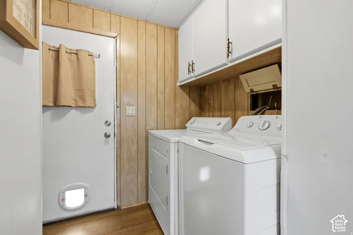 Laundry area featuring wood-finish wall panels and white cabinetry