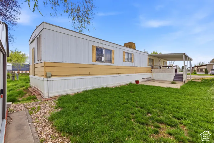 Exterior featuring horizontal siding, multiple windows, a covered patio, and a grassed yard