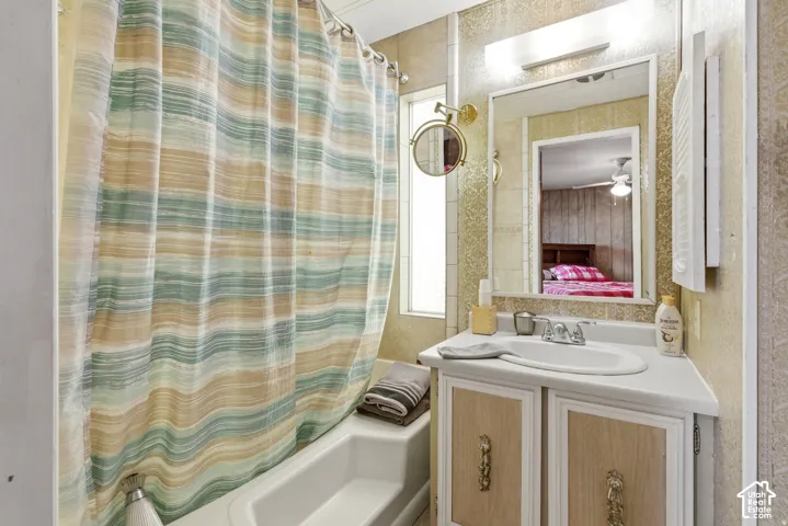 Built-in bathtub, corner vanity with integrated sink, wall-mounted mirror, and overhead vanity lighting