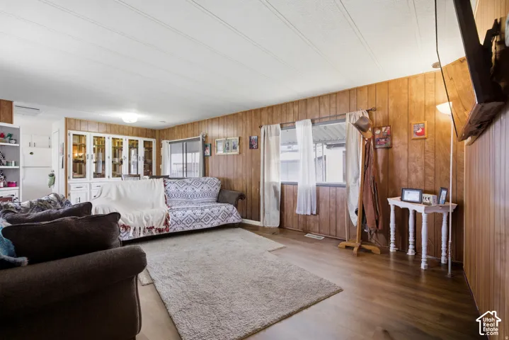 Wood-finish flooring with paneled walls, white ceiling panels, built-in display cabinetry, and multiple windows