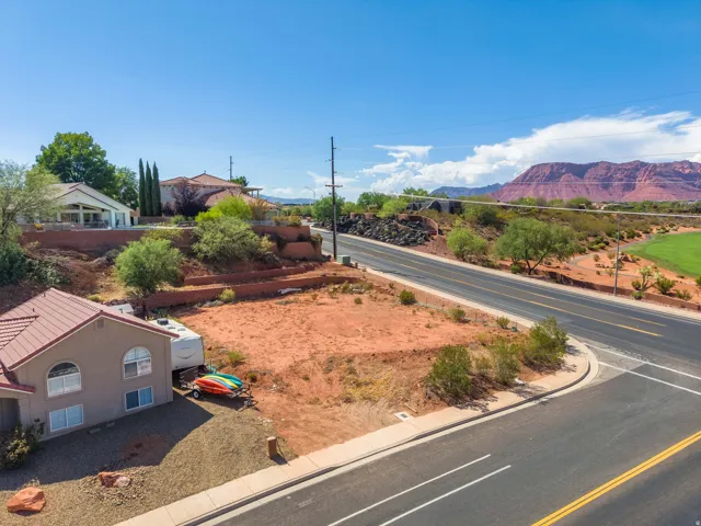 Expansive lot featuring a red rock landscape, paved roads, and distant mountain scenery