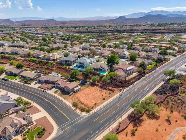 Aerial perspective of a developed neighborhood with residential properties, paved roads, and natural desert landscaping