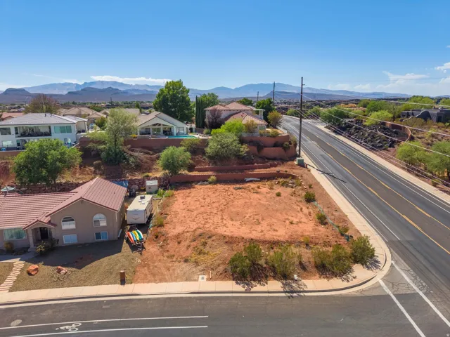 Expansive undeveloped lot with street frontage, mountain backdrop, and surrounding residential properties