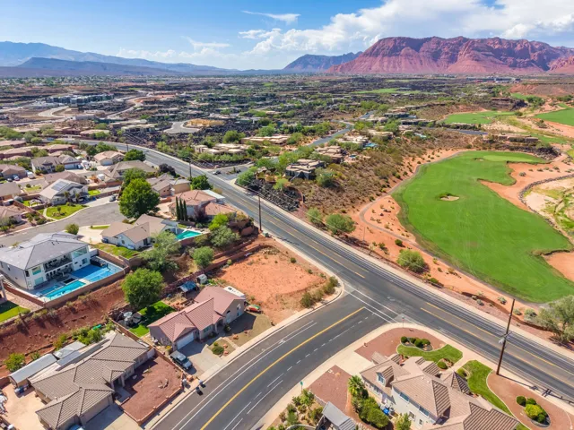 Expansive residential area featuring a prominent road, golf course, and distant mountains