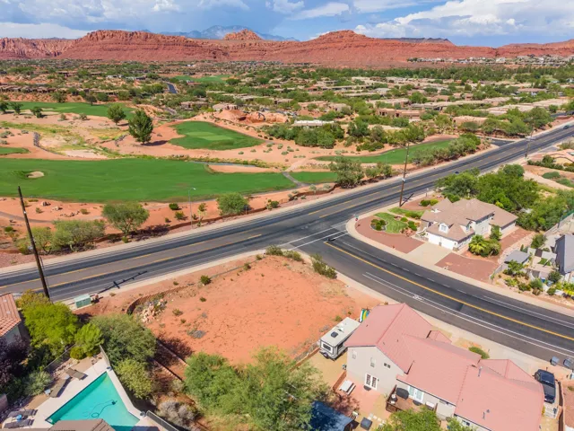 Expansive residential area featuring a golf course, paved roads, and prominent red rock formations in the background