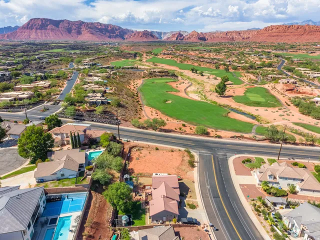 Aerial perspective showcasing residential properties, a golf course, and a prominent red rock mountain range