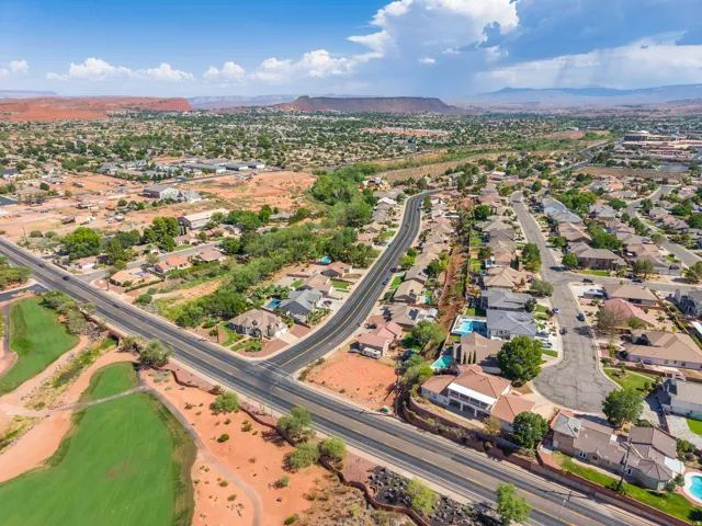 Aerial perspective showcasing a residential neighborhood with varied architectural styles, red rock landscaping, and mature trees