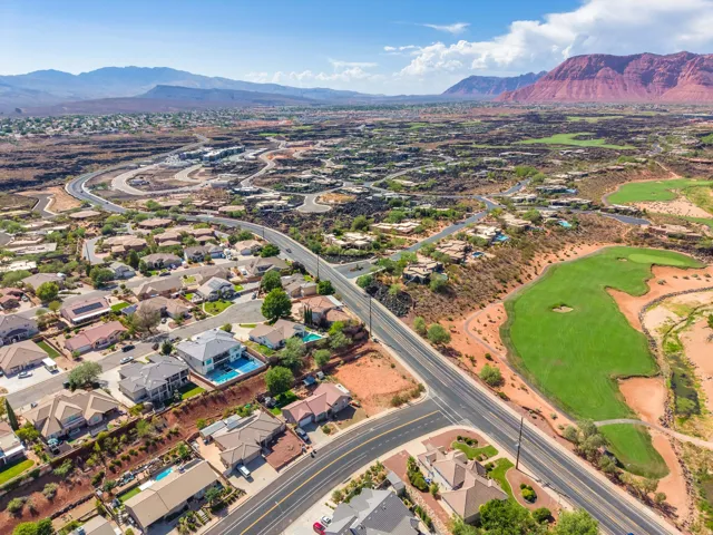 Expansive residential development with a golf course, mountain backdrop, and multiple homes featuring swimming pools
