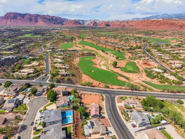 Expansive residential area featuring a golf course, substantial red rock mountains, and diverse architectural styles