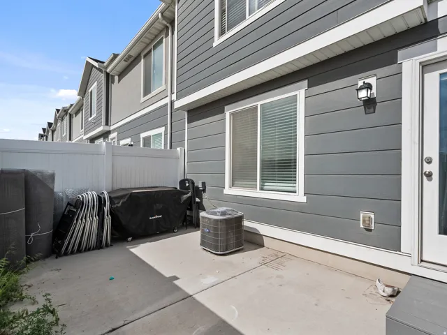 Rear patio with concrete surface, white privacy fencing, and grey siding exterior