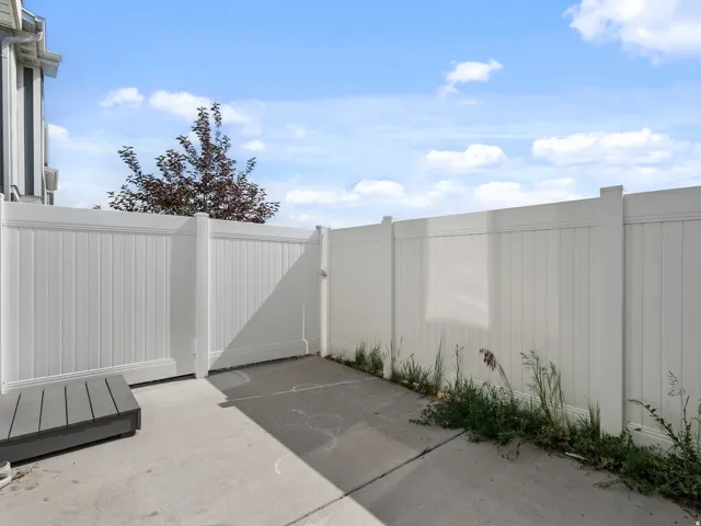Concrete patio enclosed by a white privacy fence