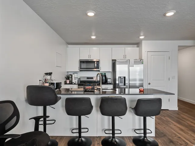 Kitchen with white cabinetry, stainless steel appliances, dark countertop, and recessed lighting