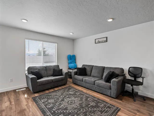Recessed ceiling lighting, wood-finish flooring, white walls, and a large window with blinds