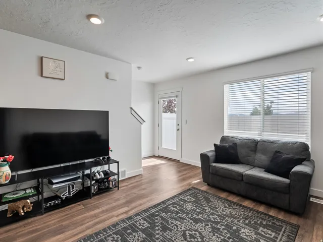 Recessed ceiling lighting, wood-finish flooring, white trim, and a white interior door