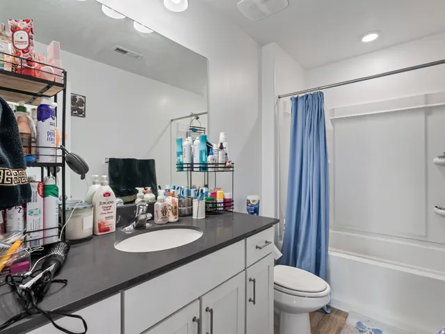 Bathroom featuring a built-in vanity with an undermount sink, dark countertop, and integrated storage