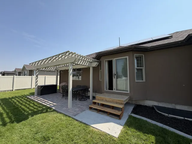 Private backyard featuring a paved patio, a pergola, a sliding glass door, and a grass lawn