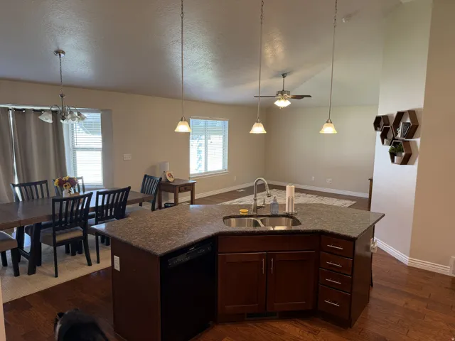 Kitchen island with integrated sink, dark wood-finish cabinetry, and pendant lighting
