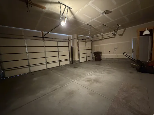Two garage bays with automatic openers, concrete flooring, and interior access door