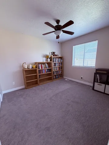 Textured ceiling with a ceiling fan light fixture, neutral wall paint, window with horizontal blinds, and wall-to-wall carpeting