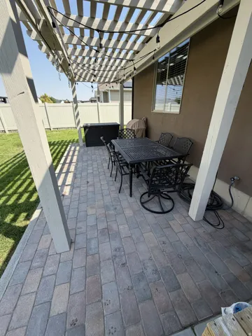 Paved patio featuring a wood pergola and a textured exterior wall
