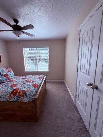 Window with blinds, ceiling fan with integrated lighting, textured ceiling, panel doors, and neutral-toned wall paint