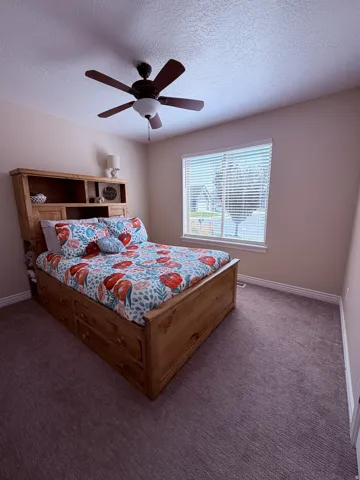 Neutral wall color, ceiling fan with integrated lighting, window with blinds, base molding, and carpeted flooring