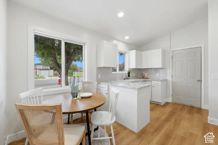 Light-filled kitchen with white cabinetry and a light-toned wood-finish floor
