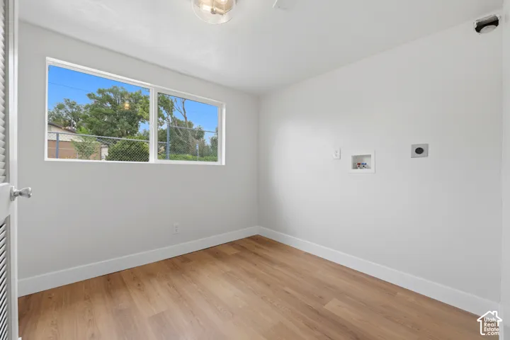 Light-filled room featuring a large window, wood-finish flooring, and white walls