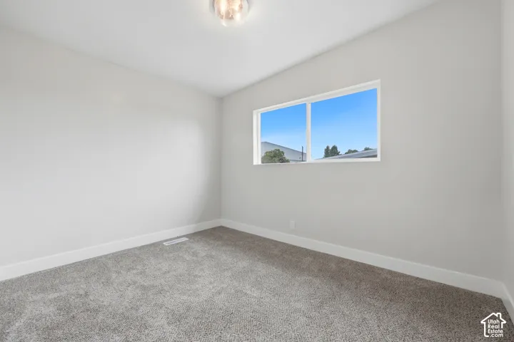 Recessed ceiling light fixture, neutral grey wall paint, plush grey carpeting, and a double-pane window
