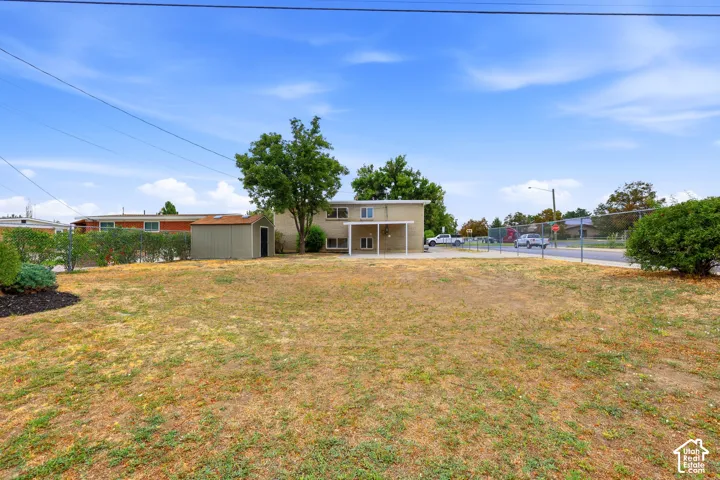 Expansive lot featuring a detached storage shed, mature trees, and a chain-link fence