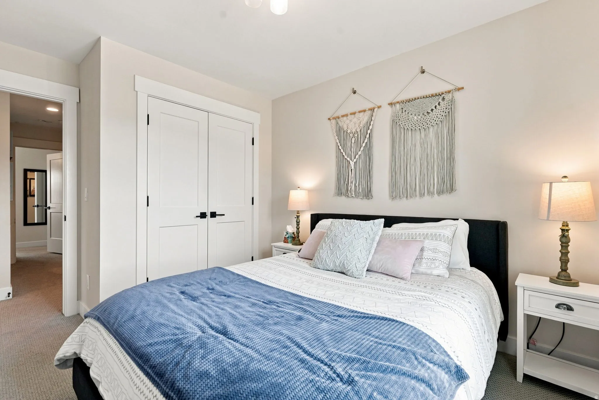 White painted double doors with black hardware, neutral wall color, and light-toned carpet flooring