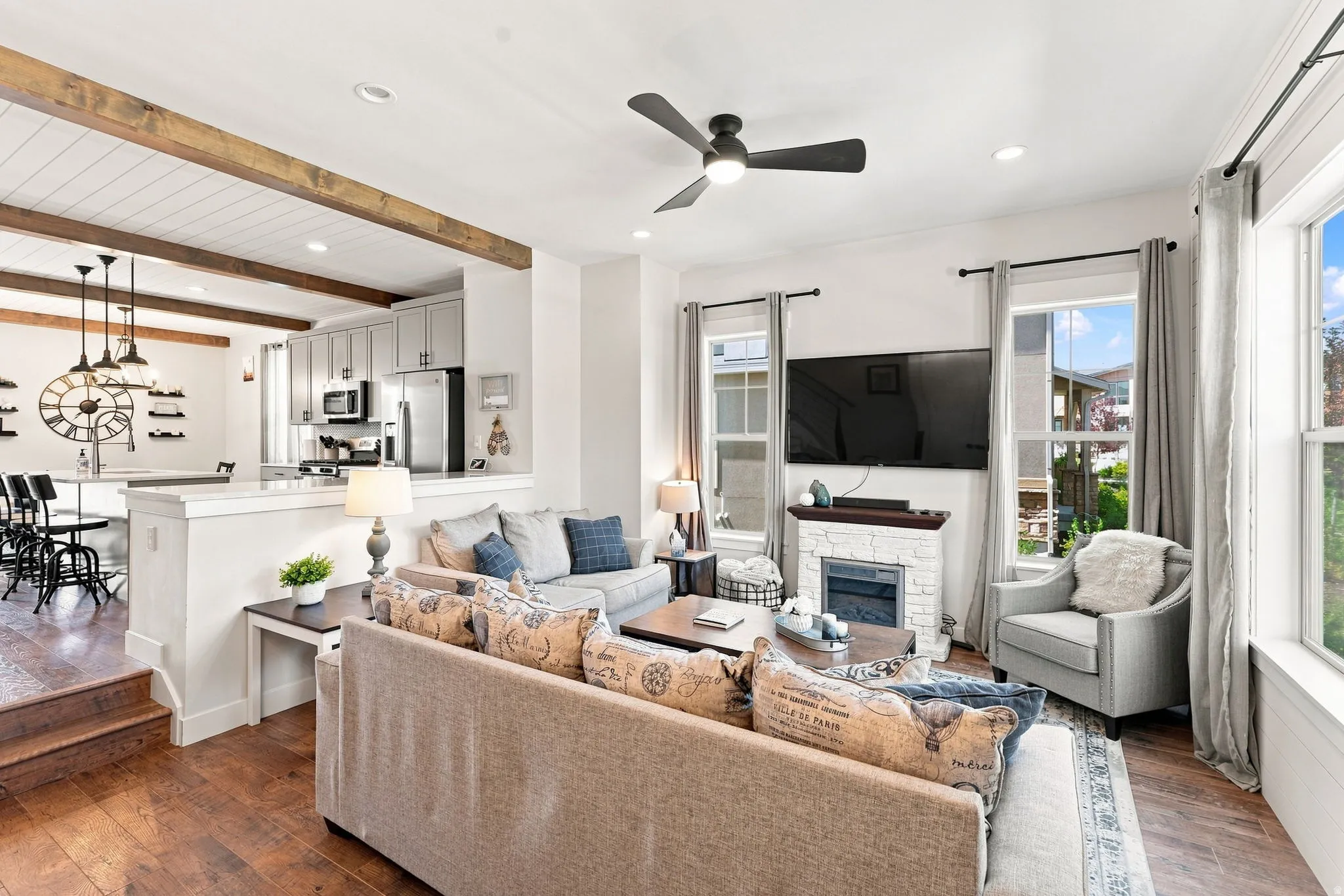 Open-concept living space featuring hardwood flooring, exposed ceiling beams, and recessed lighting